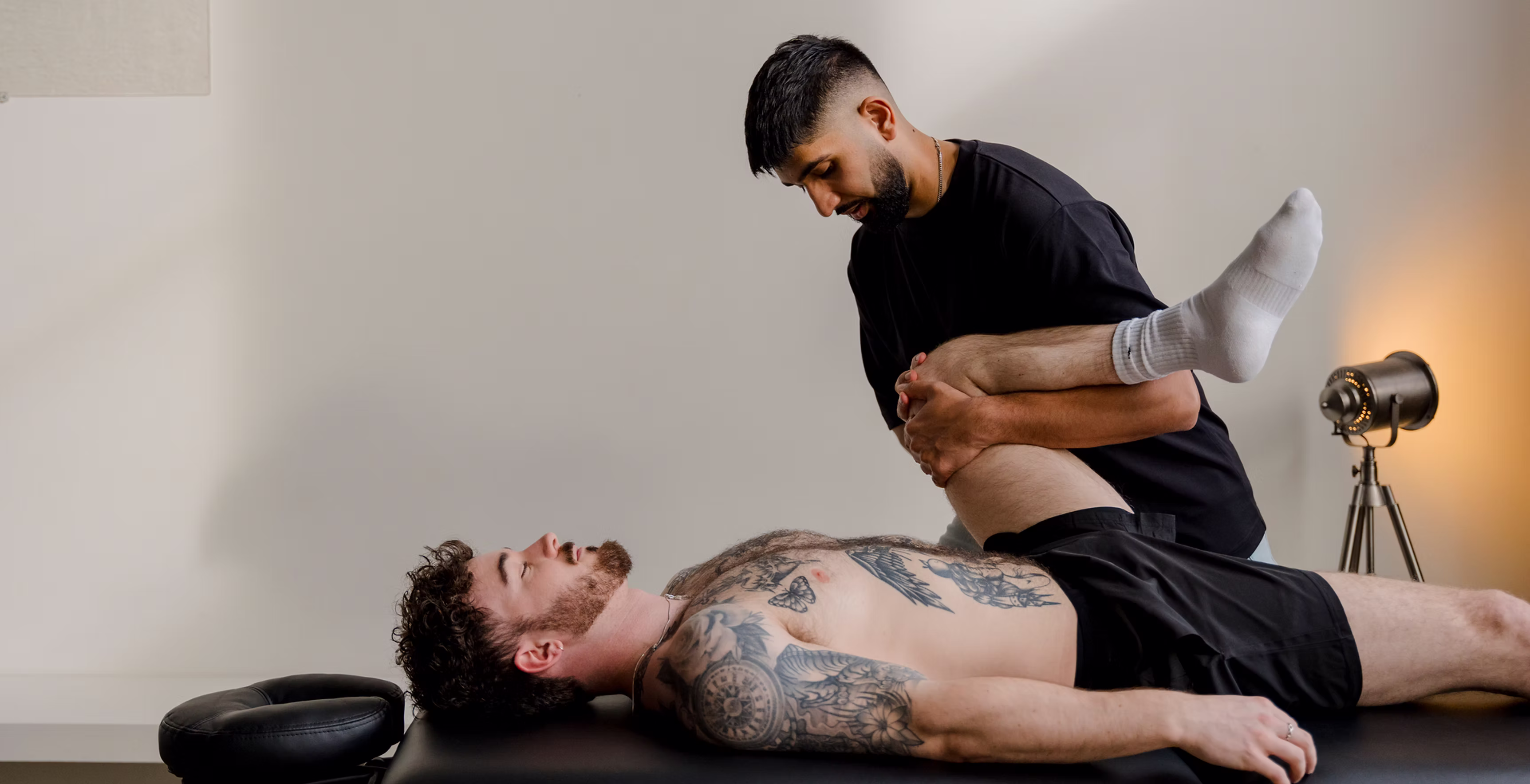 A practitioner at arc therapy mobilising a patient's hip on the treatment table